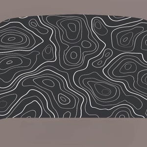 May include: Black and white topographic map pattern on a dark gray background. The pattern is made up of white lines that create a series of circles and curves.