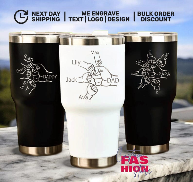 May include: Three stainless steel insulated tumblers in black and white. Each tumbler features a personalized design with names and the words "DADDY" or "PAPA" and a fist bump graphic. The tumblers have a silver rim and base.