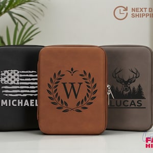 May include: Three zippered cases in black, brown, and gray. The black case features an American flag design and the name "MICHAEL". The brown case has a "W" inside a laurel wreath. The gray case has a deer graphic and the name "LUCAS".