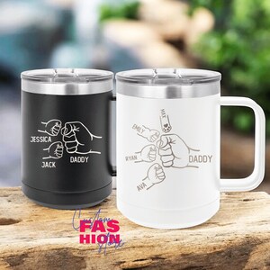 May include: Two stainless steel travel mugs, one black and one white, with silver rims and handles. The black mug has the names "Jessica", "Jack", and "Daddy" with a fist bump design. The white mug has the names "Emily", "Ryan", "Ava", "Max", and "Daddy" with a fist bump design.