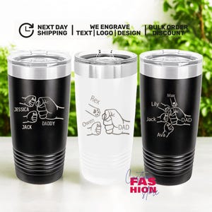 May include: Three stainless steel tumblers with lids. Two are black, one is white. Each features a fist bump design with names and the word "DAD". The text "WE ENGRAVE TEXT LOGO DESIGN" is visible.