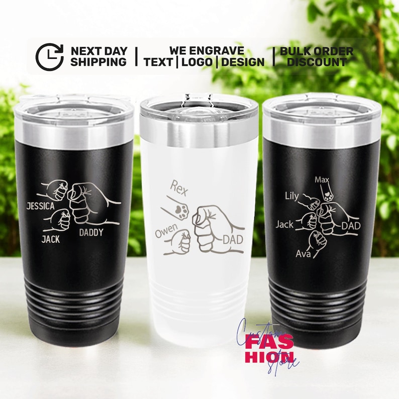May include: Three stainless steel tumblers with lids. Two are black, one is white. Each features a fist bump design with names and the word "DAD". The text "WE ENGRAVE TEXT LOGO DESIGN" is visible.