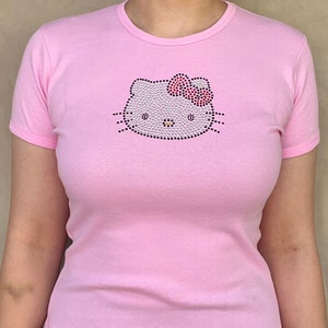 May include: A pink t-shirt with a rhinestone Hello Kitty design.