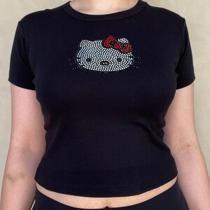 May include: Black short-sleeved t-shirt with a rhinestone Hello Kitty design.