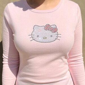 May include: A pink long-sleeved t-shirt with a rhinestone Hello Kitty design.