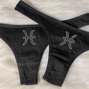 May include: Black underwear with a rhinestone Pisces zodiac sign.