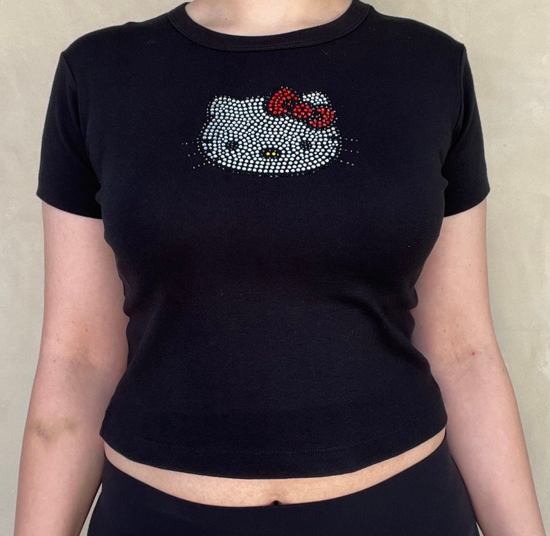 May include: Black short-sleeved t-shirt with a rhinestone Hello Kitty design.