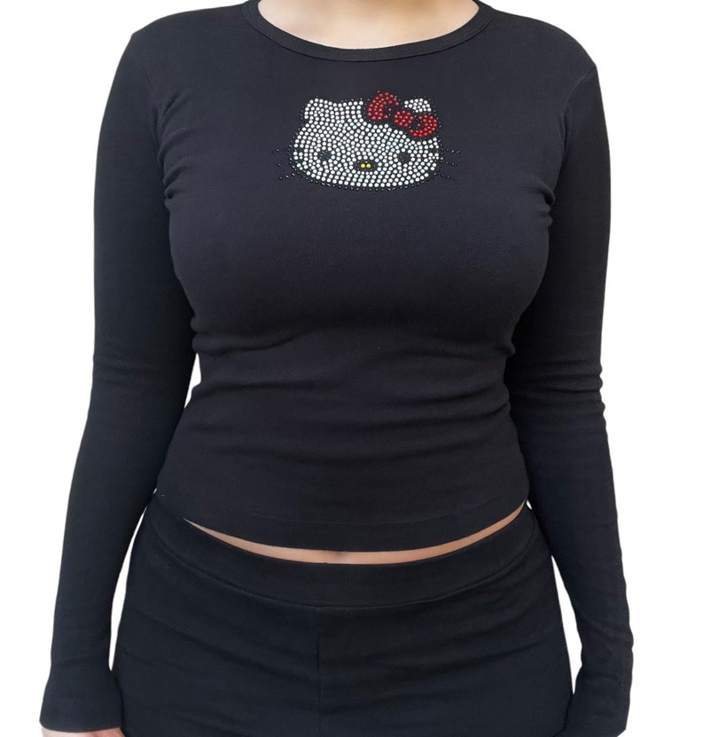 May include: Black long-sleeved shirt with a rhinestone Hello Kitty design on the front.
