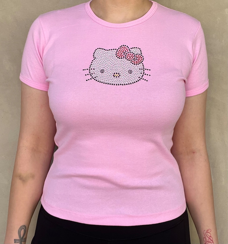 May include: A pink t-shirt with a rhinestone Hello Kitty design.