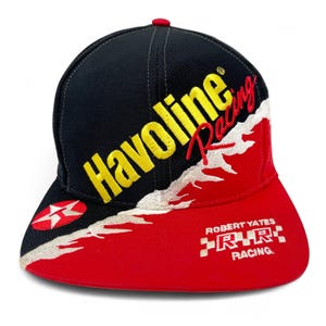 May include: Black and red baseball cap with the words "Havoline Racing" in yellow and red embroidery. The cap features a white and red star logo and the text "ROBERT YATES RRR RACING".