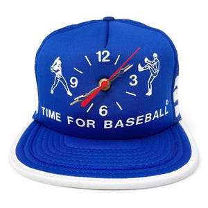May include: A blue baseball cap with a white mesh back. The front of the cap features a white clock face with a red second hand and the text "TIME FOR BASEBALL".