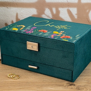 Puede incluir: Una caja de joyería verde azulada con un diseño floral y el nombre "Christie" en la tapa. La caja tiene un cajón y una cerradura.