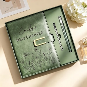 Può includere: Un set di diario verde salvia in una scatola coordinata, dotato di una chiusura in metallo dorato e un design floreale a linee sottili. La copertina reca la scritta Emily's NEW CHAPTER. Il set include una penna verde abbinata e un refill sottile.