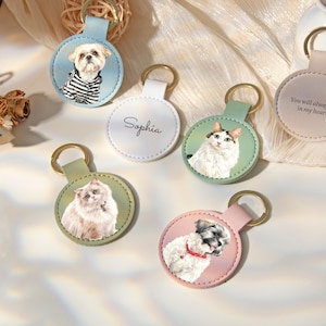 Puede incluir: Seis llaveros circulares de cuero con anillas de metal dorado. Uno muestra un perro con camisa a rayas, otro el nombre Sophia, uno un gato blanco, uno un gato esponjoso, uno un perro blanco con collar rojo y otro dice You will always be in my heart.