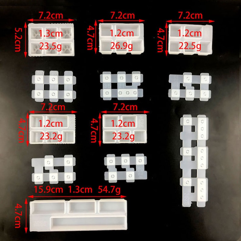 May include: A collection of clear, rectangular silicone molds for crafting. The molds vary in size and shape, with measurements in centimeters and grams. Some molds have paw prints, while others have multiple compartments. The image is on a black background.