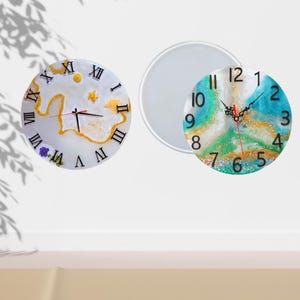 May include: Two clock faces, one with Roman numerals and a white background with gold accents, and the other with Arabic numerals and a blue, green, and gold background. Both clocks have black hands.