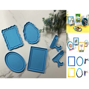 Op de afbeelding: Een set blauwe siliconen mallen voor het maken van hars fotolijsten. De mallen omvatten verschillende vormen, waaronder ovale, rechthoekige en vierkante lijsten, evenals twee verschillende ezelstandaards.