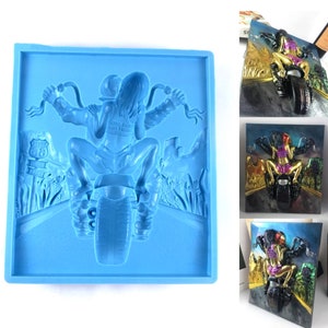 May include: A light blue silicone mould depicting a motorcycle and rider. The rider is wearing a jacket and shorts, with long hair. The background shows a road and a sign reading "Route 66".