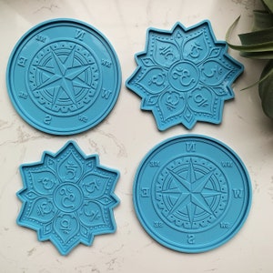 May include: Four blue silicone moulds for resin casting. Two moulds feature a compass design with the directions N, S, E, and W. The other two moulds feature a mandala design with the Sanskrit word Om in the centre.