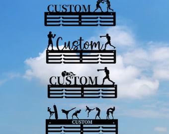 May include: Four black metal medal display racks with a custom name and a silhouette of a boxer or martial artist on each rack. The racks are against a blue sky background.