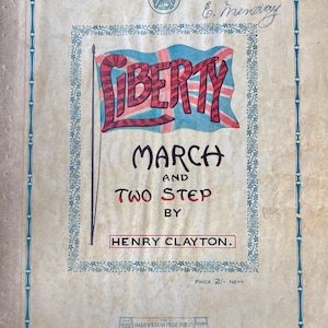 Pode incluir: Uma capa de partitura vintage intitulada Liberty March and Two Step de Henry Clayton. A capa apresenta uma ilustração da bandeira Union Jack, uma borda decorativa azul e texto indicando que este solo de piano inclui partes de violino, corneta e baixo.