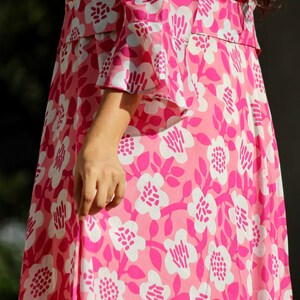 May include: A pink dress with a white floral pattern. The dress has a fitted bodice and a flowing skirt.