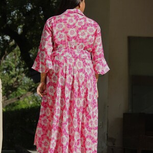 May include: A pink and white floral print dress with a long skirt and 3/4 sleeves. The dress has a fitted bodice and a flowy skirt.