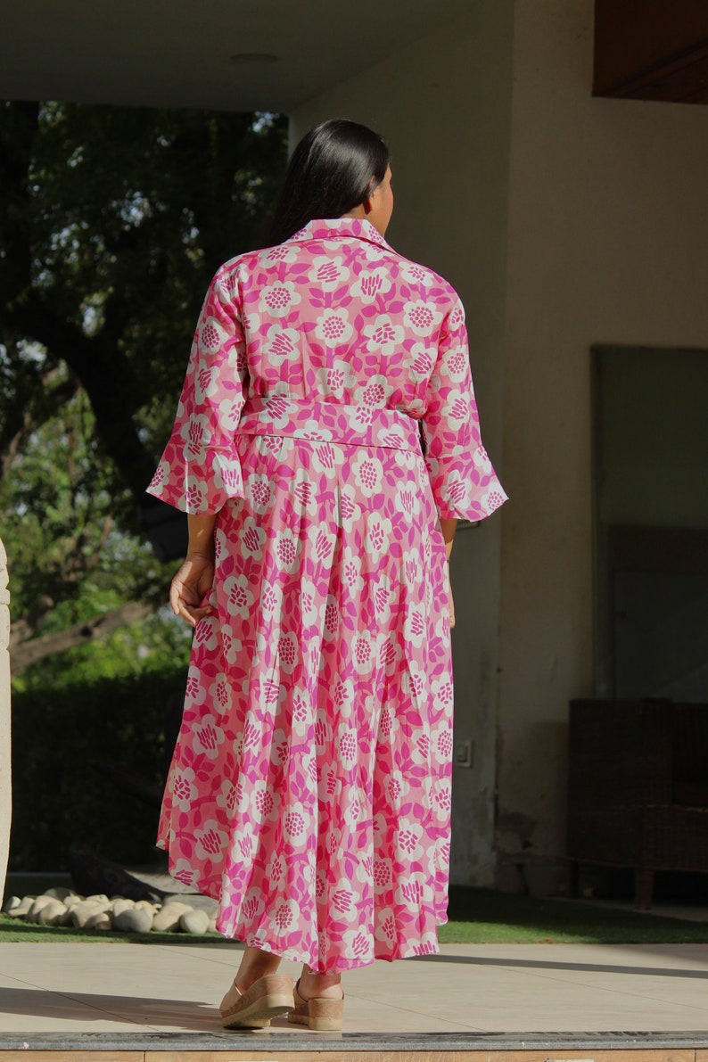 May include: A pink and white floral print dress with a long skirt and 3/4 sleeves. The dress has a fitted bodice and a flowy skirt.