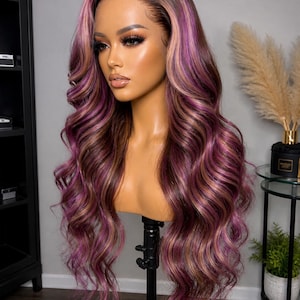 May include: A long, wavy wig with a dark brown root and highlights of purple and light brown. The wig is styled on a mannequin head, showcasing its layered curls and natural-looking hairline. The wig is designed for fashion and beauty.