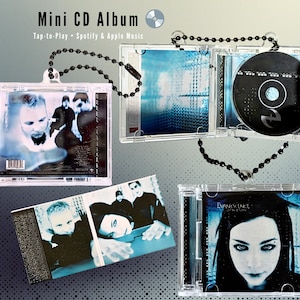 Puede incluir: Mini álbum de CD en estuches de plástico transparente con cadena de cuentas negras. La carátula del álbum presenta a los miembros de la banda y las portadas de los álbumes. El texto "Mini CD Album" y "Tap-to-Play Spotify & Apple Music" es visible.