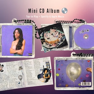 Puede incluir: Mini álbum de CD en una funda transparente con una cadena de cuentas negras. La portada del álbum presenta a una persona sobre un fondo morado. El CD es morado con la palabra "SOUR". El álbum incluye un folleto con letras e imágenes. El texto de la imagen dice "Mini CD Album".