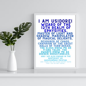 Op de afbeelding: Een ingelijst print met een blauw en wit tekstontwerp. De tekst luidt "Ik ben Usidore! Tovenaar van het 12e rijk van Ephysiyies, meester van licht en schaduw, manipulator van magische genoegens, verslinder van chaos, kampioen van de grote hallen van Terr' Akkas. De elven kennen me als Fiang Yalok. De dwergen kennen me als Zoenen Hoogstandjes. En ik ben ook bekend in het noordoosten als Gaismunenanas Meistar. En er kunnen andere geheime namen zijn die je niet kent..."