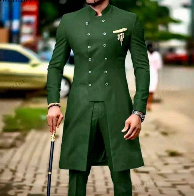 May include: A dark green suit with a double-breasted jacket and a mandarin collar. The jacket has a long, flowing style and features a decorative gold pin.