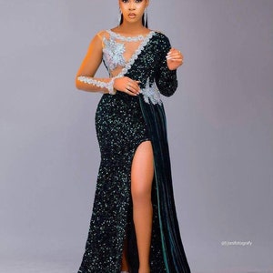 May include: A woman wearing a long, green sequined gown with a sheer, silver-embellished bodice. The gown has a thigh-high slit and a flowing train. The woman is wearing silver earrings and has her hair pulled back.