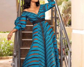 May include: A woman wearing a long, blue and orange patterned dress with a black belt. The dress has a V-neckline and long sleeves. She is standing on a set of stairs.