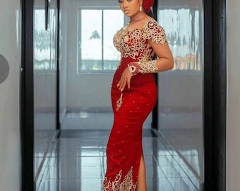 Puede incluir: Una mujer con un vestido rojo con bordados dorados y un turbante rojo. El vestido tiene una abertura en el lateral y la mujer está de pie en un pasillo.