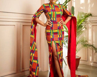May include: A woman wearing a long, red and yellow patterned dress with a high neck and long sleeves. The dress has a slit up the front and the sleeves are very long and flowy. The woman is standing in front of a pink wall.