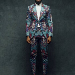 May include: A man wearing a blue patterned suit with a white shirt and sunglasses.