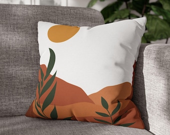 May include: A white throw pillow with a minimalist design featuring a yellow circle, green leaves, and orange and brown hills.