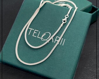 Puede incluir: Un collar de cadena de plata en una caja verde con la palabra "TELQARII" impresa en ella.