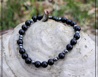 Puede incluir: Un brazalete de cuentas negras y plateadas con cuentas de ónix negro y hematites.