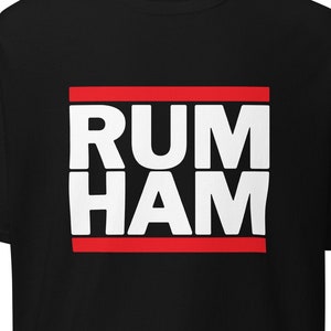 May include: Black t-shirt with a red and white box featuring the text "RUM HAM" in white letters.