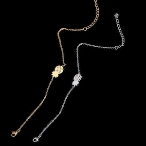 May include: Two delicate gold and silver pineapple charm bracelets with a chain link design.