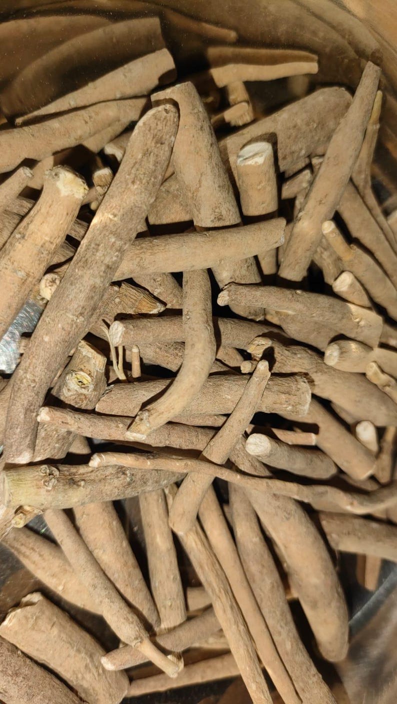 May include: Close-up of a pile of light brown, dried, and cut ashwagandha roots. The roots vary in size and shape, with some showing cut ends. The image is well-lit, highlighting the natural texture and color of the roots.