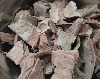 May include: A collection of dried, irregular pieces of tree bark with a rough, textured surface and varying shades of light brown, tan, and reddish-brown, contained within a smooth, reflective, metallic silver-colored bowl.