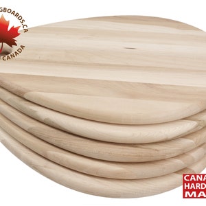 May include: A stack of five round wooden chopping boards made from Canadian hardwood maple. The boards are all the same size and have a slightly rounded edge. The top board has a small hole in the centre.