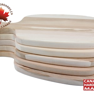 May include: A stack of eight natural wood chopping boards with rounded edges and a handle. The boards are made of Canadian hardwood maple. The boards are stacked on a white background. The text "BLK CUTTINGBOARDS.CA MADE IN CANADA" is on a red maple leaf logo.