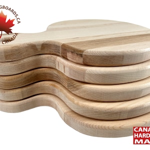 May include: A stack of five round wooden chopping boards with a handle. The boards are made of maple wood and have a natural finish. The boards are stacked on top of each other, with the top board slightly offset from the others. The boards are all the same size and shape. The boards are made in Canada. "BLK CUTTINGBOARDS.CA MADE IN CANADA" is printed on the top board. "CANADIAN HARDWOOD MAPLE" is printed on the bottom board.