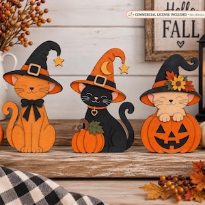以下が含まれることがあります： ハロウィンの装飾用の木製猫の置物3体。1体目は黒い魔女の帽子をかぶり星をつけたオレンジ色の猫。2体目はオレンジ色の魔女の帽子をかぶり月と星をつけた黒猫で、カボチャの横に座っている。3体目はカボチャの中に入っている猫。