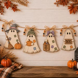 Puede incluir: Una guirnalda decorativa con cuatro figuras de fantasmas de madera suspendidas en un cordel con lazos de yute y cuentas. Los fantasmas llevan sombreros, una escoba, calabazas, una bolsa de dulces y un letrero que dice BOO, con parches de colores.